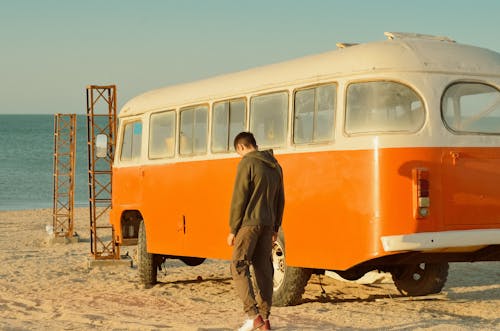 Man Standing Near Bus on Beach