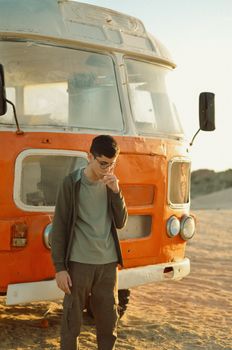 Teenager standing pensively by a vintage bus on a sandy road in Baku, Azerbaijan.