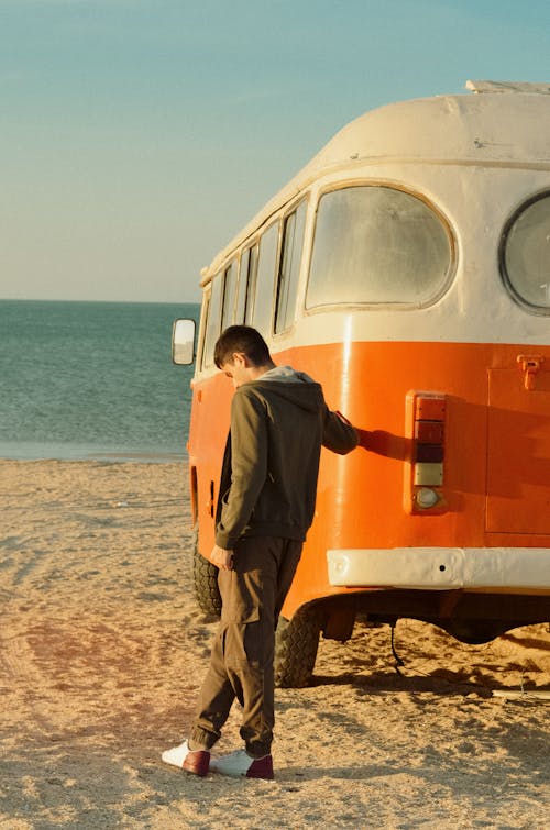 Man in Jacket Standing Next to Bus on Beach