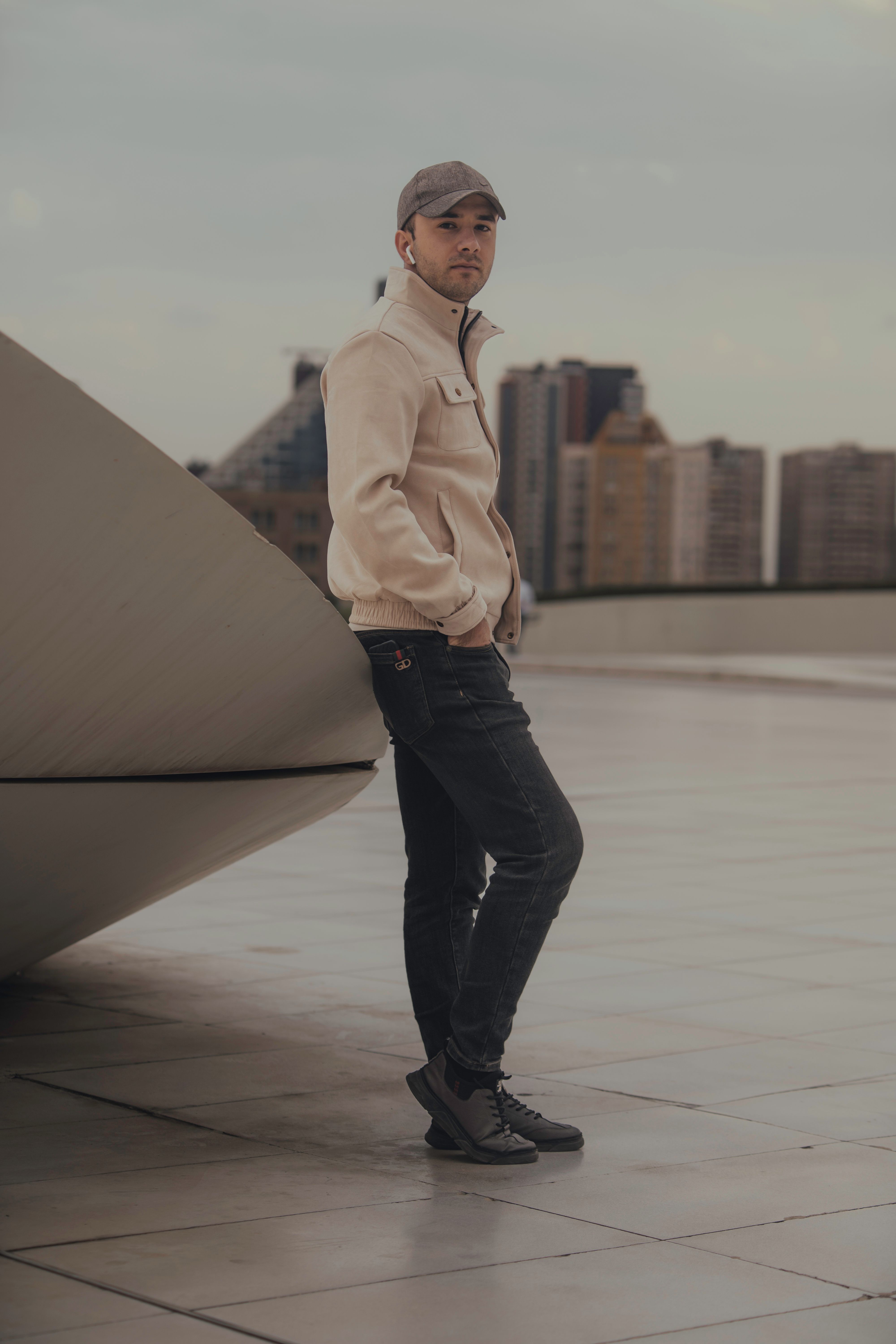 Stylish man in urban setting with modern architecture, casual wear.