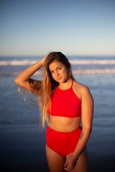 日落时分，一位身着红色比基尼的女人在海滩上享受时光的肖像