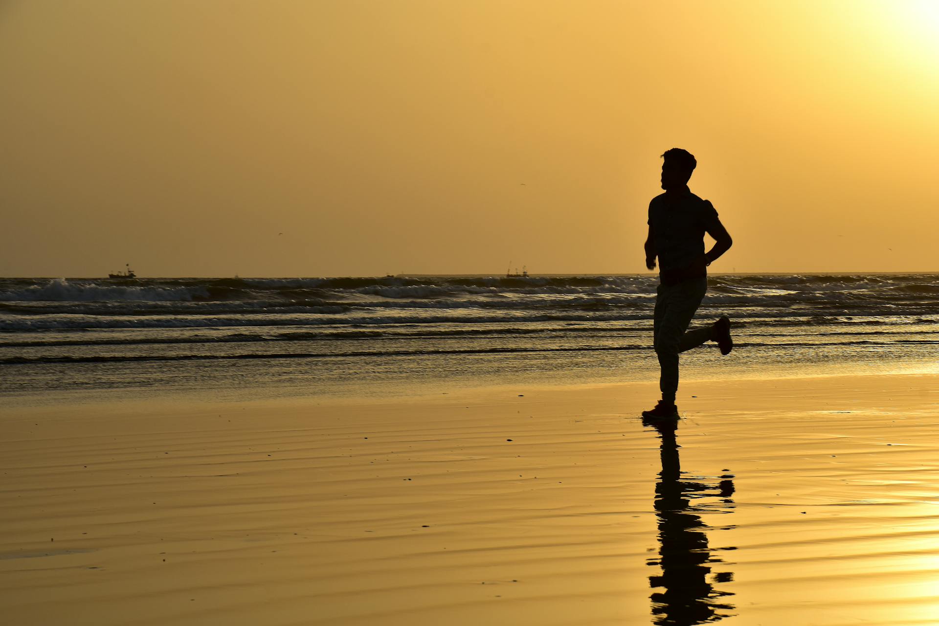 Silhouette of a man jogging on the beach in Karachi, Pakistan during sunset.