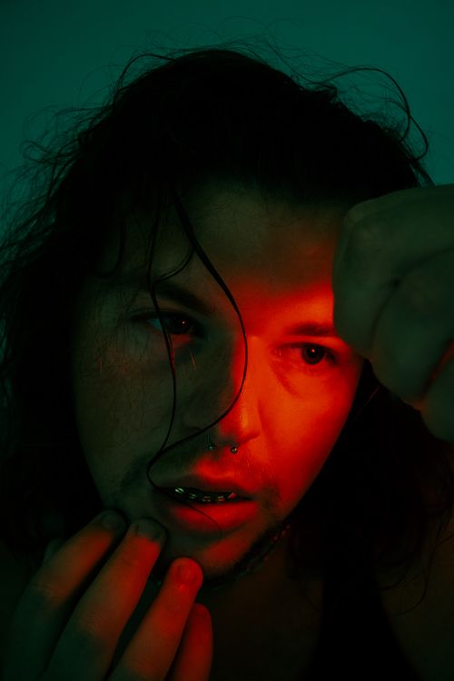 Free Close-up portrait of a person under dramatic red lighting with intense expression. Stock Photo