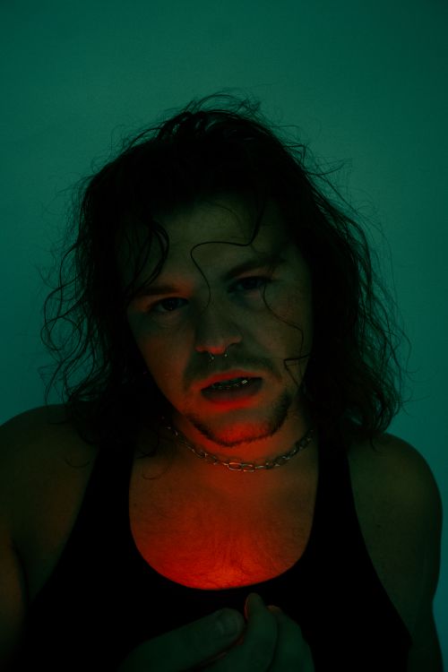 Free A moody portrait of a man with long hair, chain necklace, and dramatic lighting. Stock Photo
