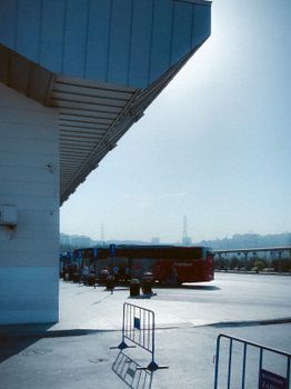 A serene morning view of an urban bus terminal with buses and city skyline in the background.