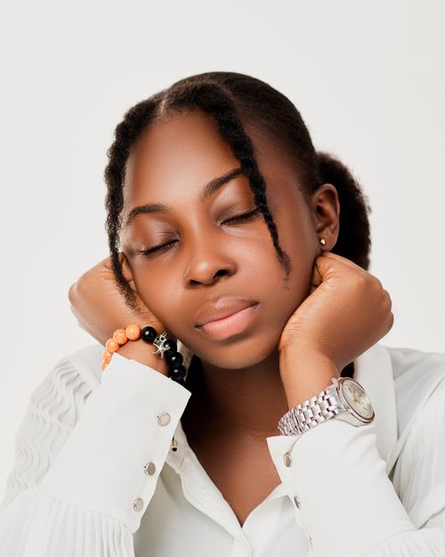 Free Peaceful portrait of an African woman with closed eyes, resting on her hands against a white background. Stock Photo