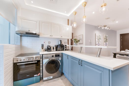 Stylish modern kitchen interior with white cabinets, blue island, and contemporary appliances.