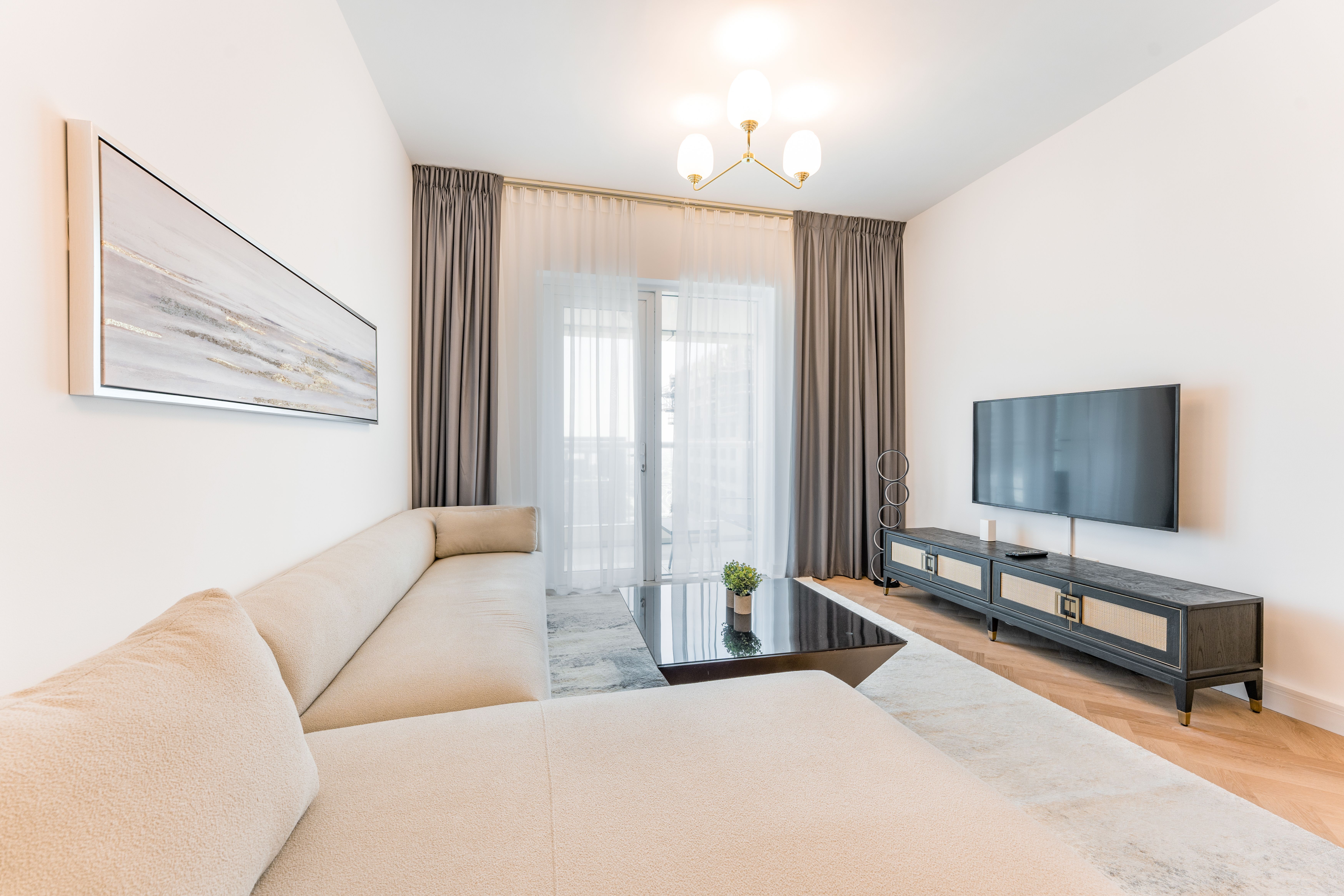 A bright, modern living room featuring a large sofa, TV, and elegant minimalist decor.