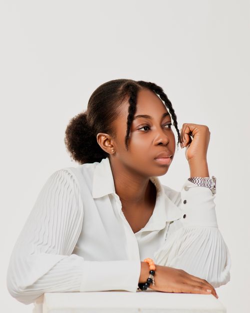 Free Portrait of an African woman in white blouse, contemplating indoors with neutral background. Stock Photo