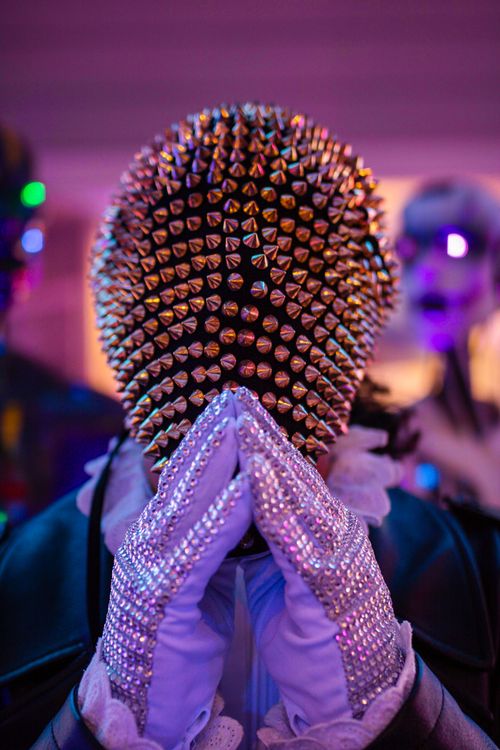 Free A person wearing a spiked mask and glittering gloves creates a mysterious, theatrical atmosphere. Stock Photo