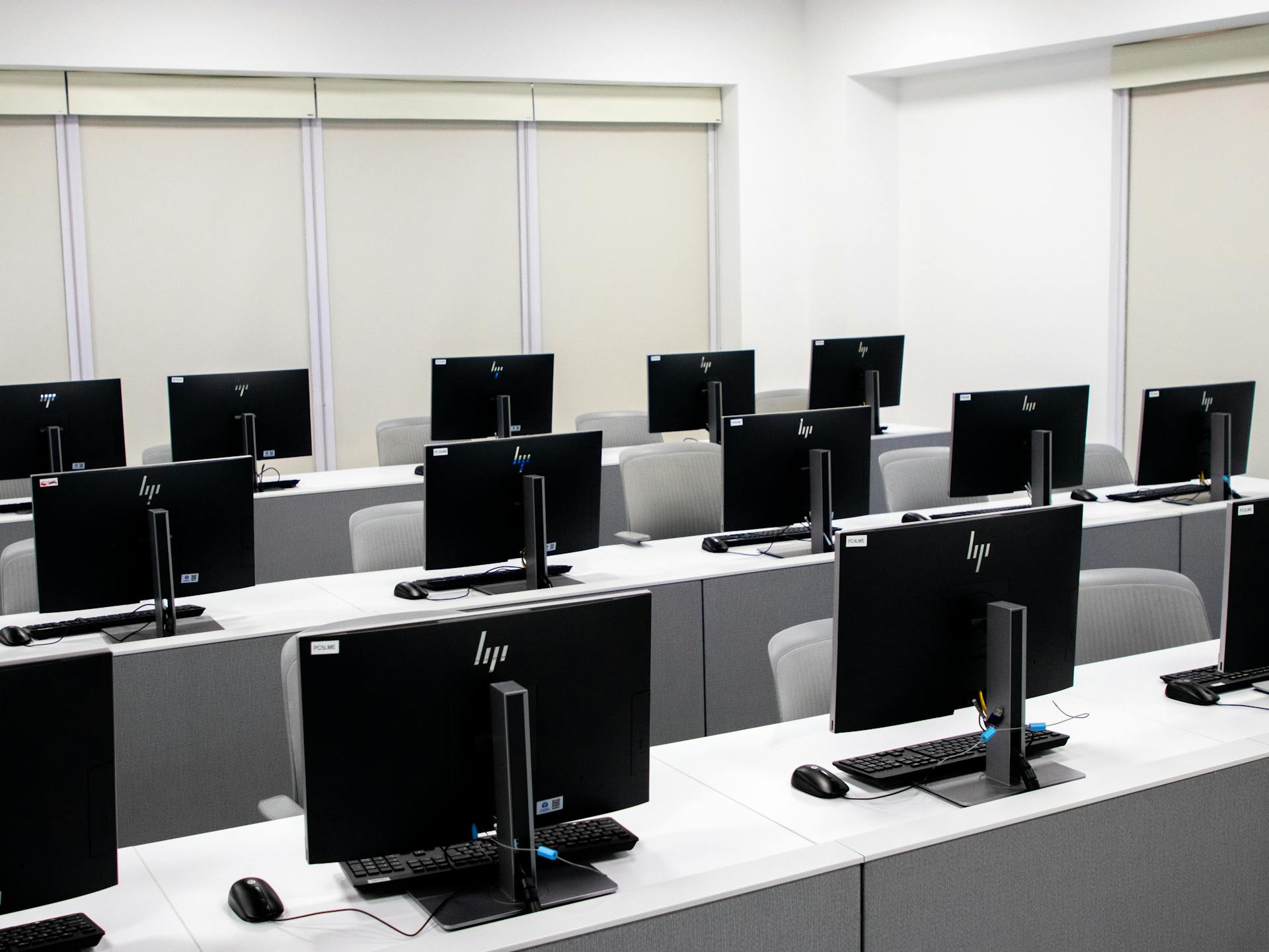 Spacious and minimalist computer lab with rows of black monitors and sleek furniture.