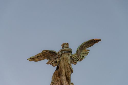 Free Majestic angel sculpture with outstretched wings under a clear blue sky in Rome, Italy. Stock Photo