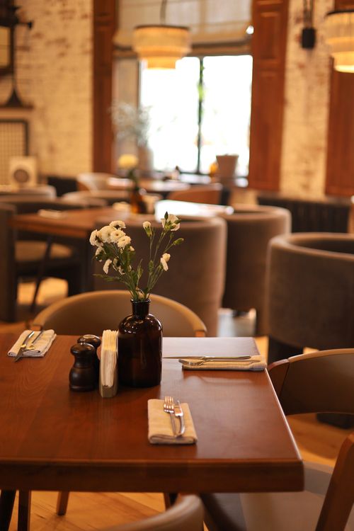 Free An inviting restaurant table set with cutlery and flowers, ideal for a cozy dining experience. Stock Photo