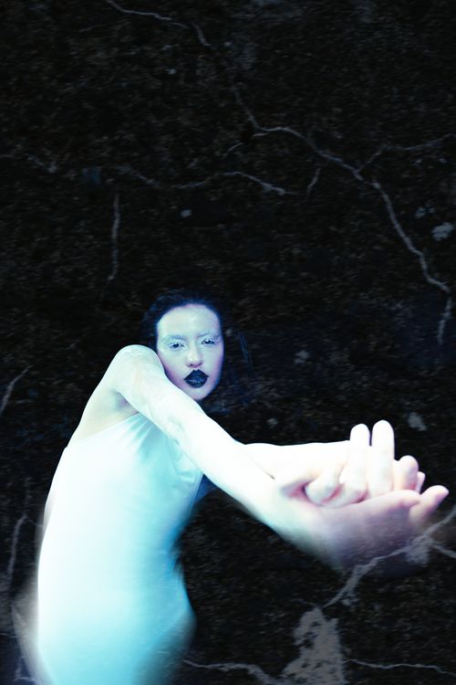 Free Striking portrait of a woman in white with black lipstick and extended arms. Stock Photo