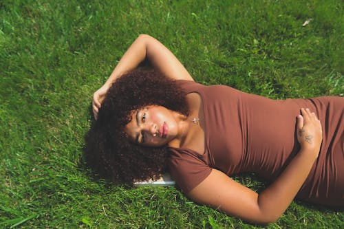 Woman with Curly Hair Lying Down on Grass