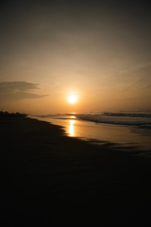 Free Captivating sunrise over a calm beach with gentle waves and golden skies, perfect serene scenery. Stock Photo