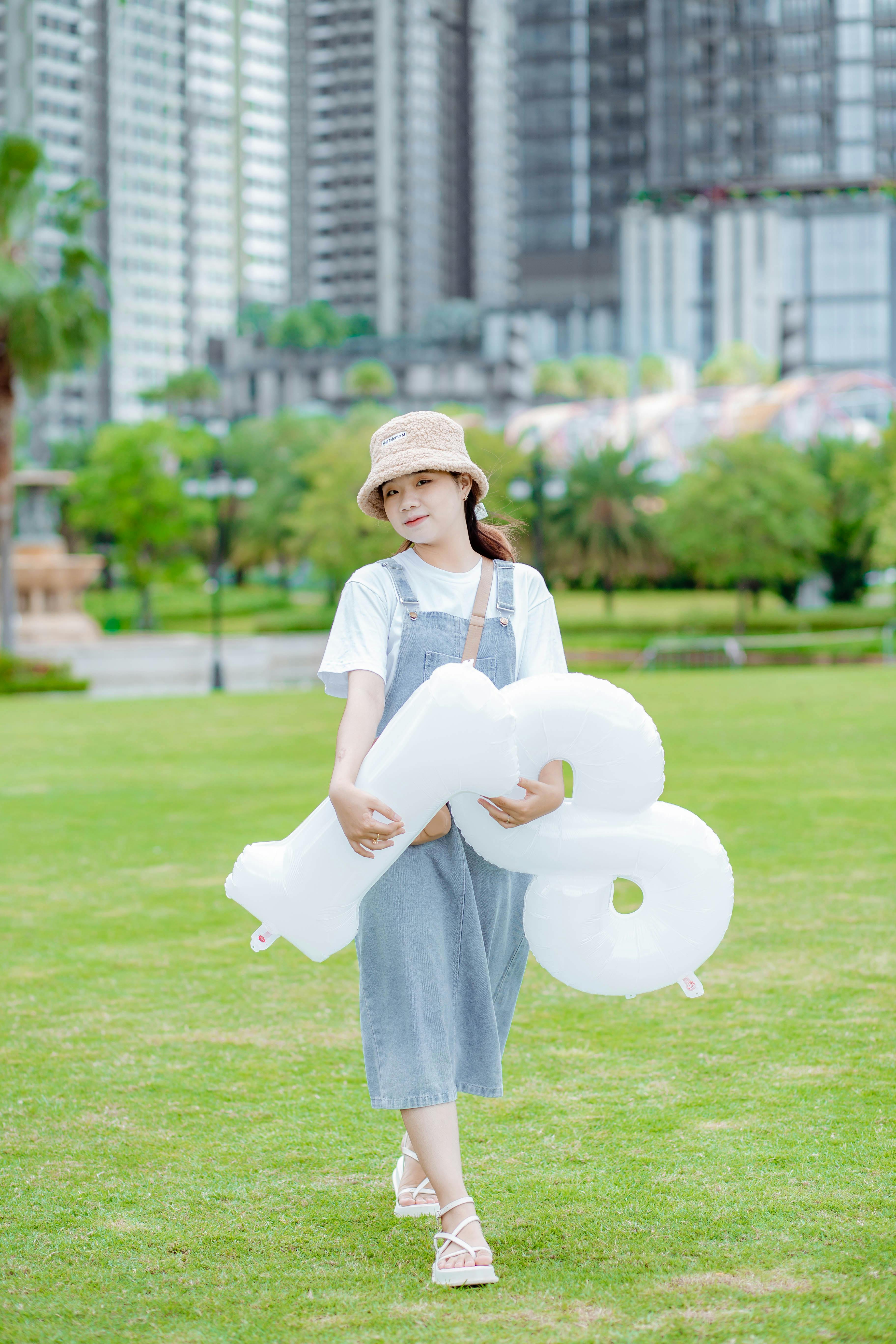 brunette teenage girl posing with balloons in park