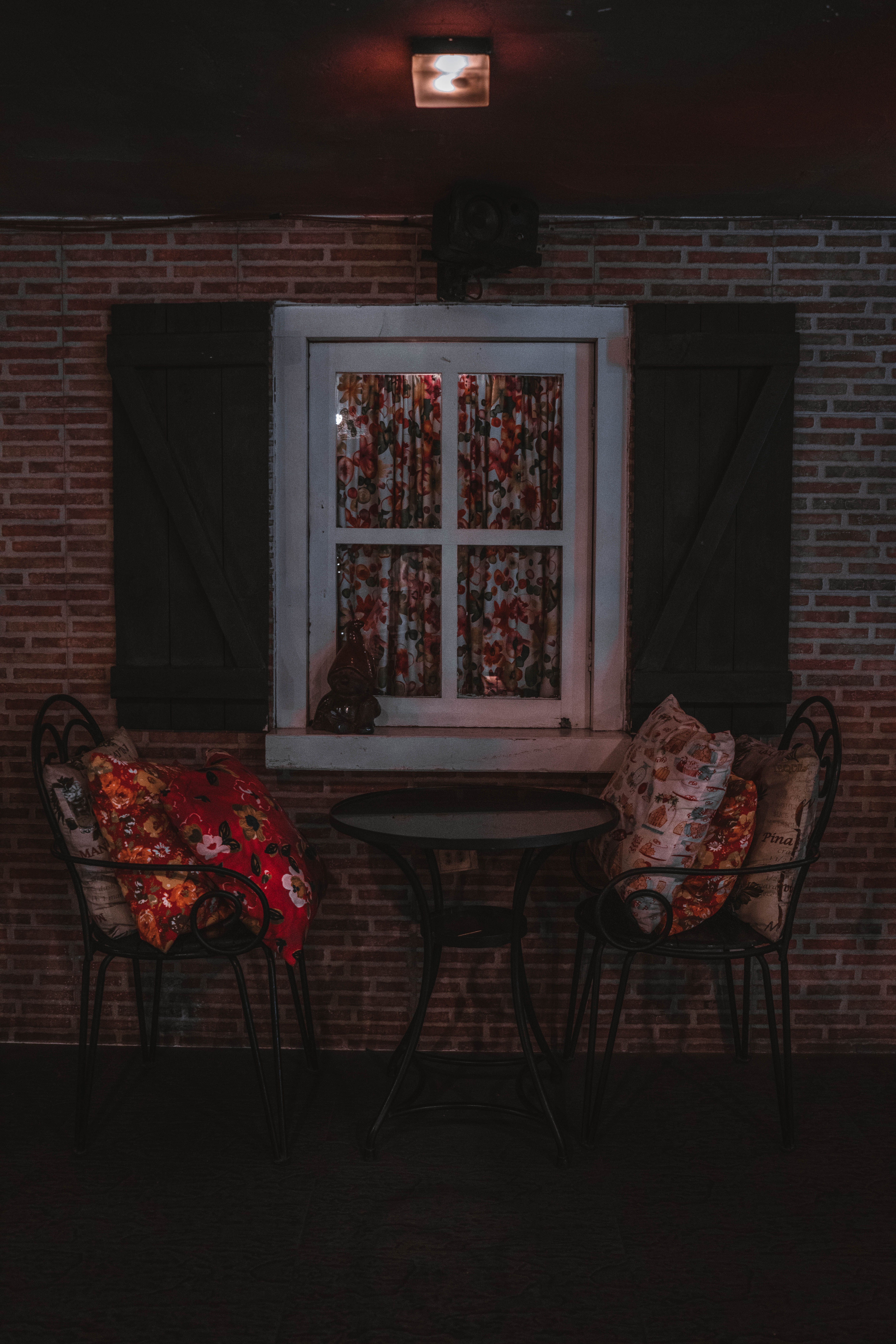Bright patterned outdoor pillows arranged on a thrifted metal patio chair on a small budget patio