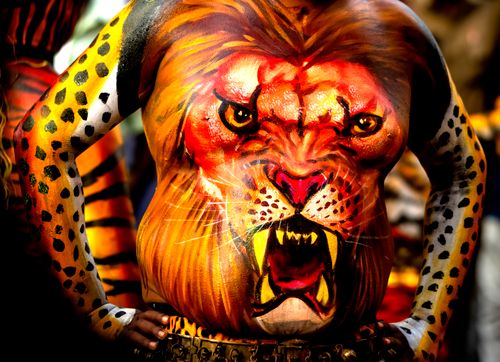 Free Close-up of painted body featuring a lion face, vibrant body art from Thrissur, India festival. Stock Photo