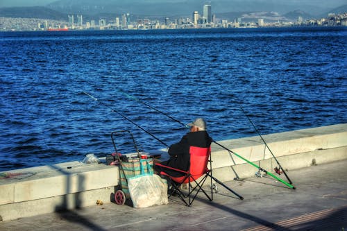 Angler with Few Fishing Rods in City Bay