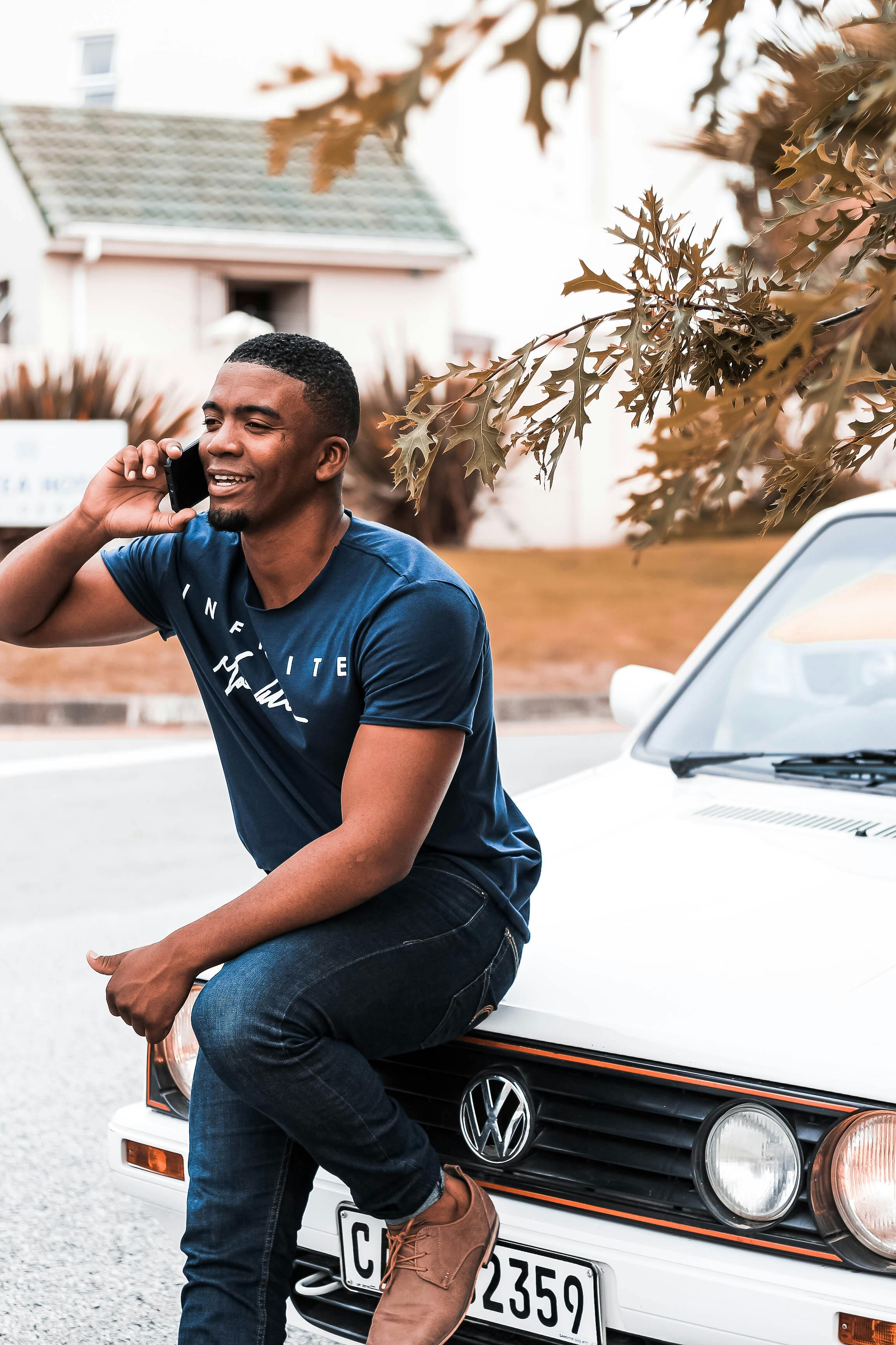 一个人在户外坐在车里，微笑着打电话