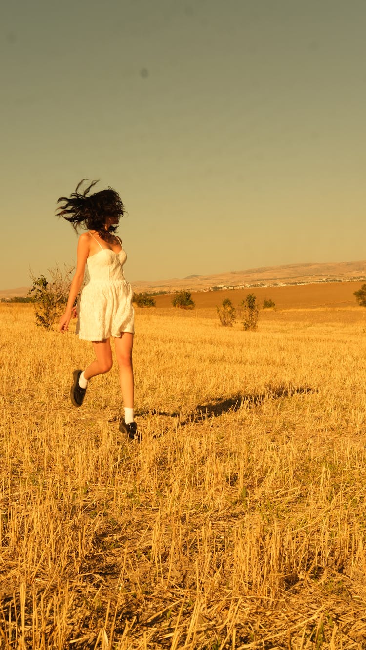 Model In A White Summer Dress Running In The Field