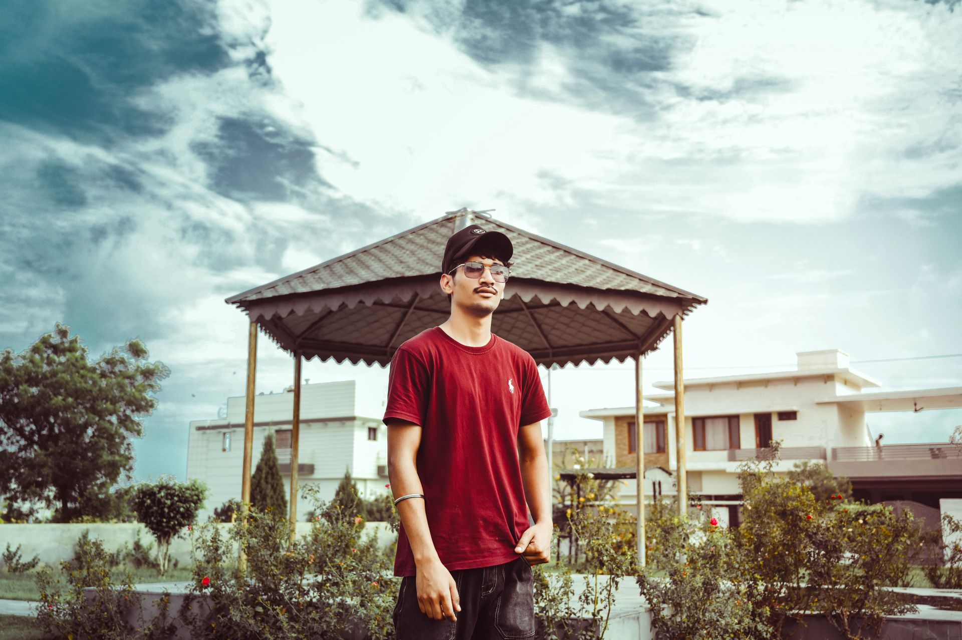 Casual portrait of a man with sunglasses and cap in an urban gazebo setting, Barnala, India.