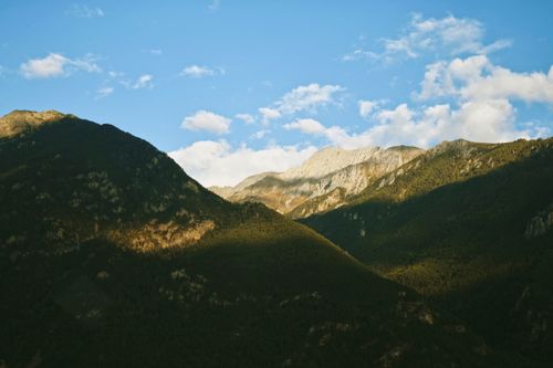 Free Aerial view of a scenic mountain range under a vibrant blue sky with scattered clouds. Stock Photo