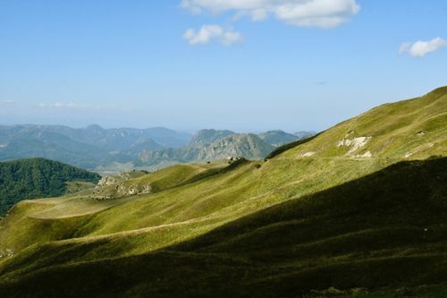 Free A breathtaking aerial view showcasing serene green hills and distant mountain ranges under a clear blue sky. Stock Photo