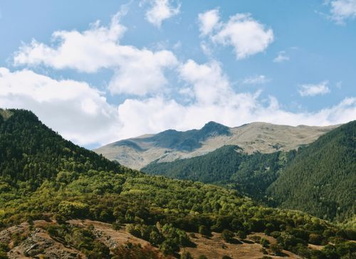 Free Stunning aerial landscape of lush green mountains under blue skies. Stock Photo