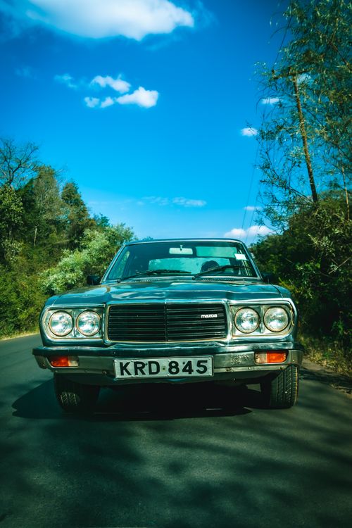Free A classic Mazda car parked on a rural road in Ngong, Kenya under a clear blue sky. Stock Photo