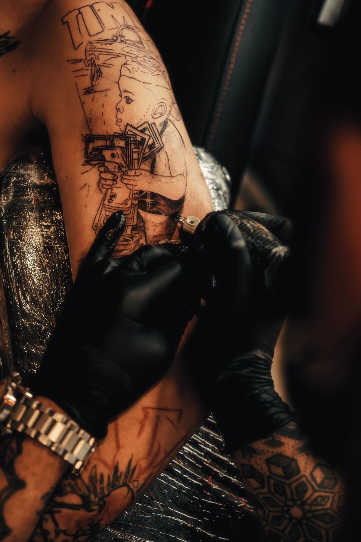 Gloved hands working a fine-line piece on a forearm