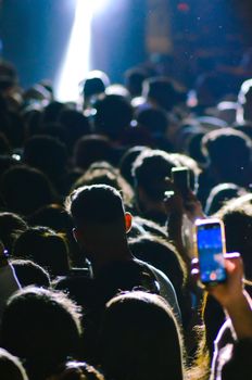Silhouetted crowd in İstanbul capturing a night event on smartphones.