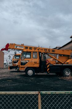 Yellow crane vehicle parked in Toyohashi, Japan industrial area, urban setting.