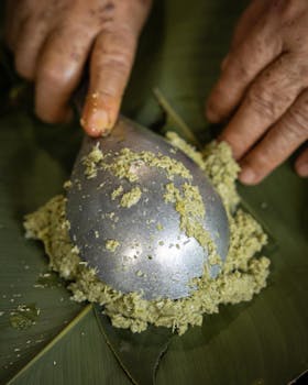 Hands mashing food on banana leaves with a spoon in Peru. Traditional cooking method displayed.
