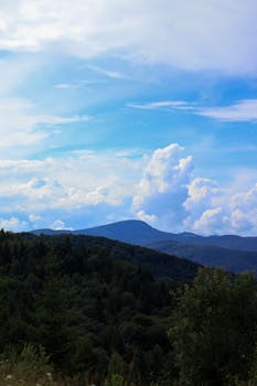 Explore a serene mountain view with lush forests and a vibrant sky, perfect for nature enthusiasts.