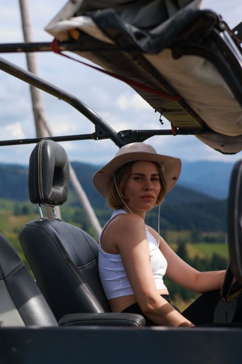 Free Young woman in a convertible enjoying a summer drive through mountainous landscapes. Stock Photo
