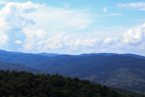 Free Stunning landscape of rolling hills and lush forest under a vast sky. Stock Photo