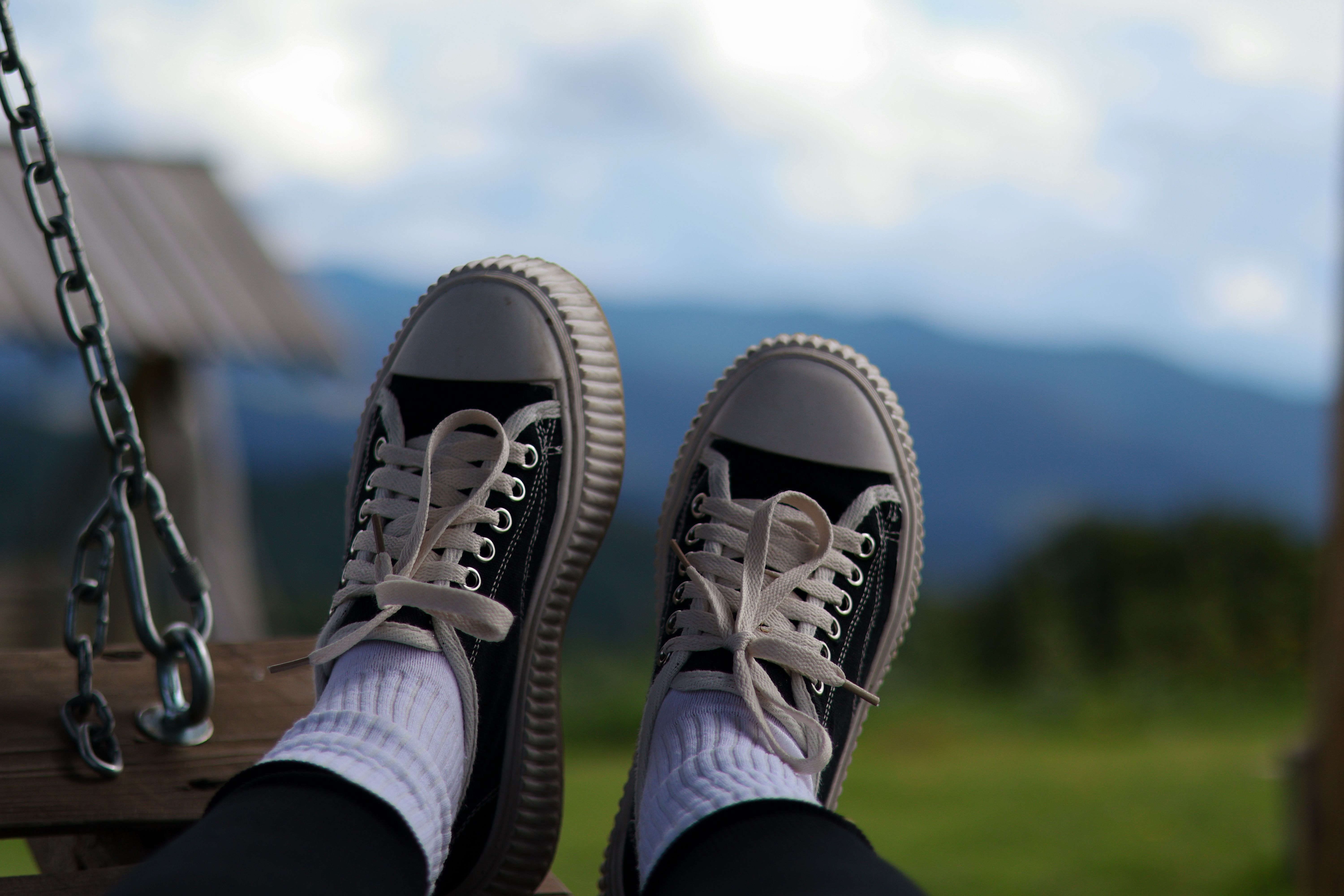 Person relaxing on a swing with feet up, enjoying countryside views.