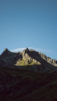 Captivating view of rugged mountain peaks illuminated by sunlight against a clear blue sky.