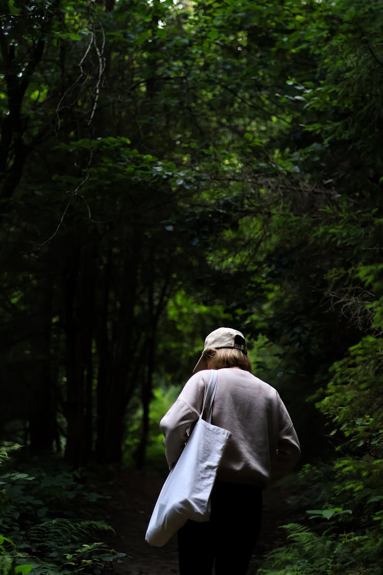 Woman With Bag Walking Through Forest In Summer