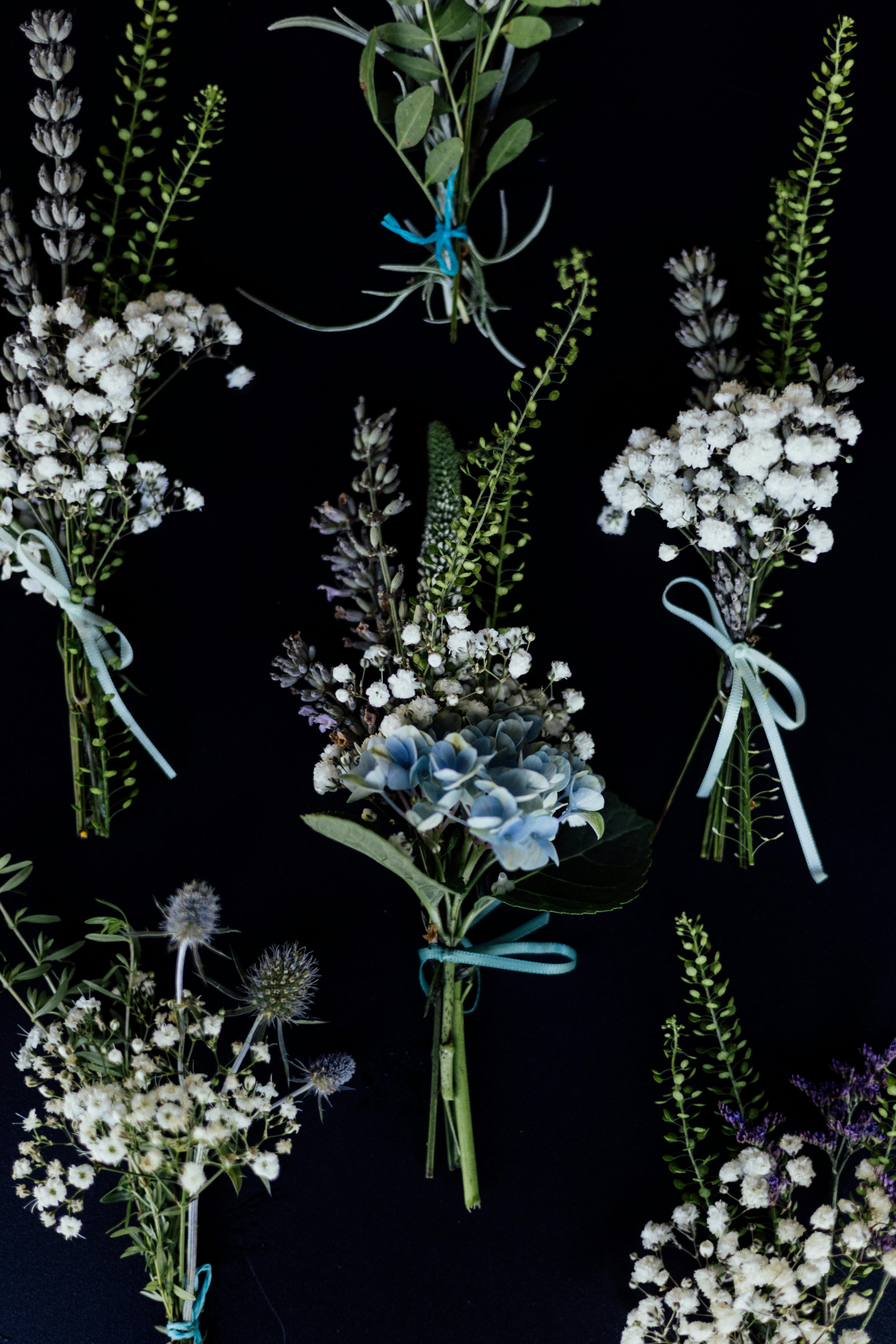 Aerial shot of elegant floral arrangements with ribbons against a black backdrop.