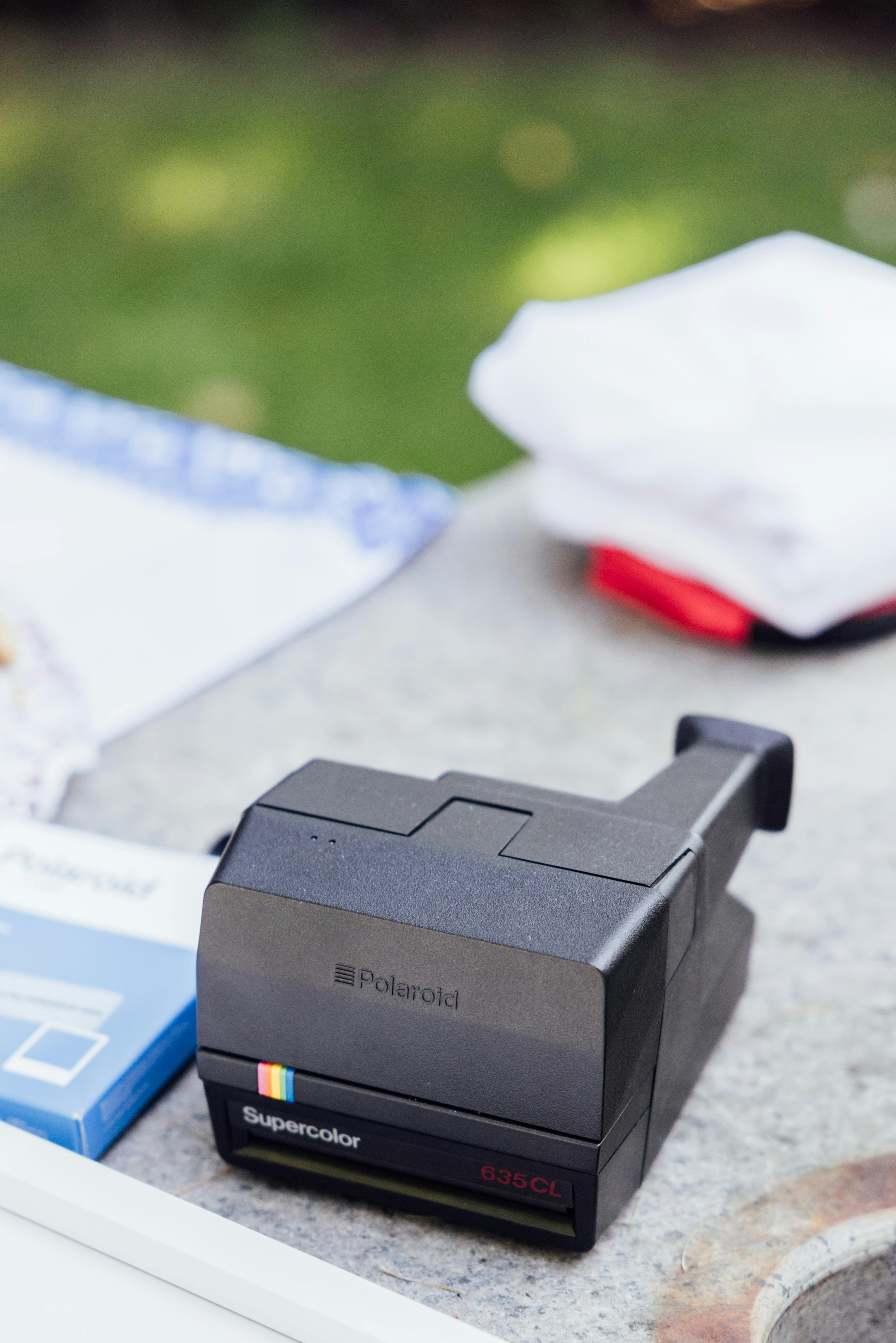 Vintage Polaroid camera on a stone table outdoors, evoking nostalgia.