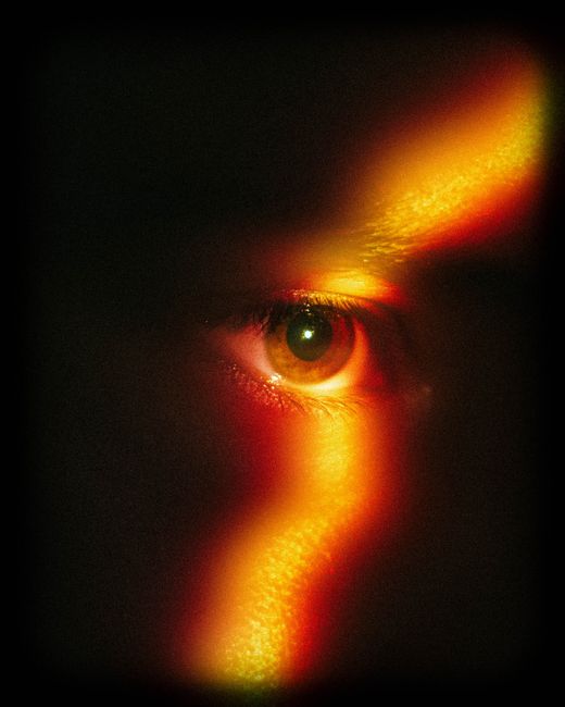 A captivating close-up of an eye with dramatic rainbow light effect in warm tones.