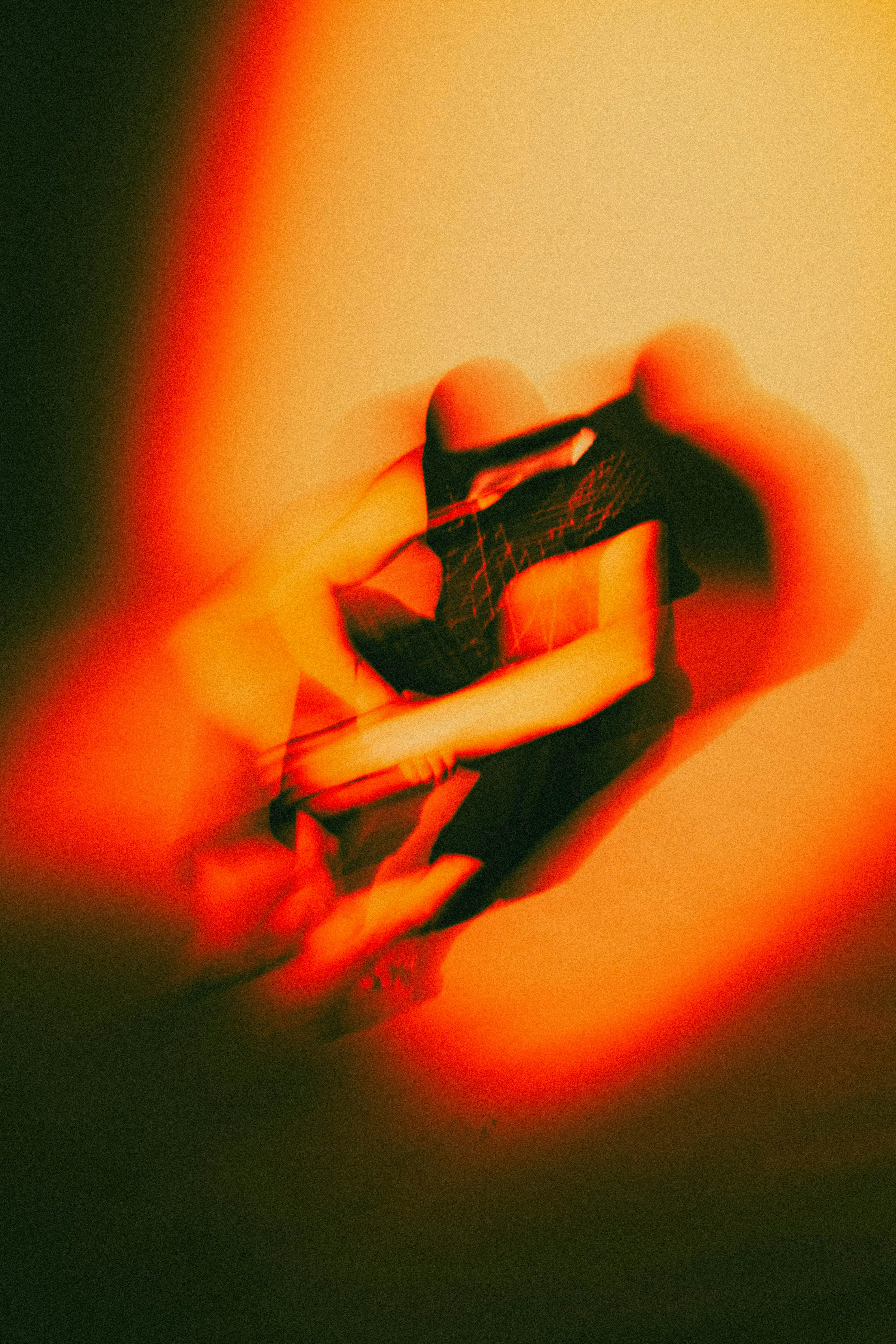 An artistic abstract image with blurred orange light and shadowy shapes, creating a dynamic visual effect.