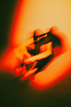 An artistic abstract image with blurred orange light and shadowy shapes, creating a dynamic visual effect.