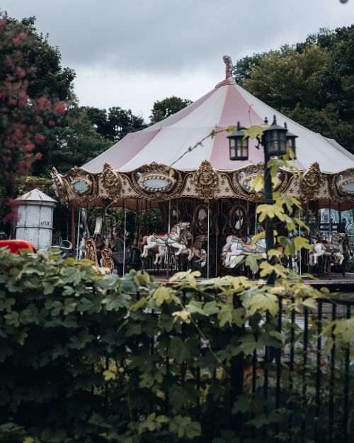 Free A nostalgic view of a vintage carousel amidst greenery at an abandoned theme park. Stock Photo