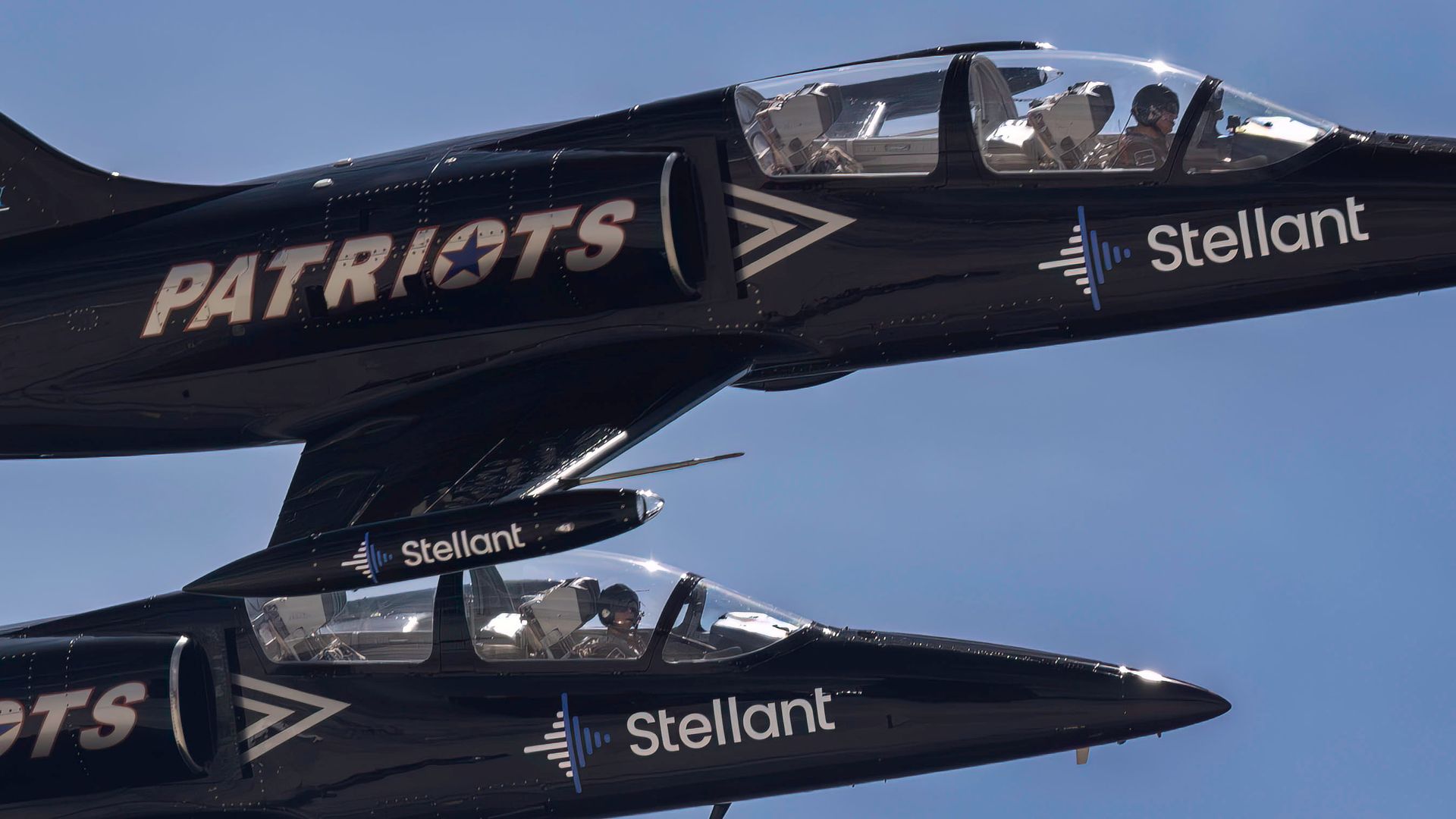 Two black Patriots Jet Team aircrafts performing in clear skies.