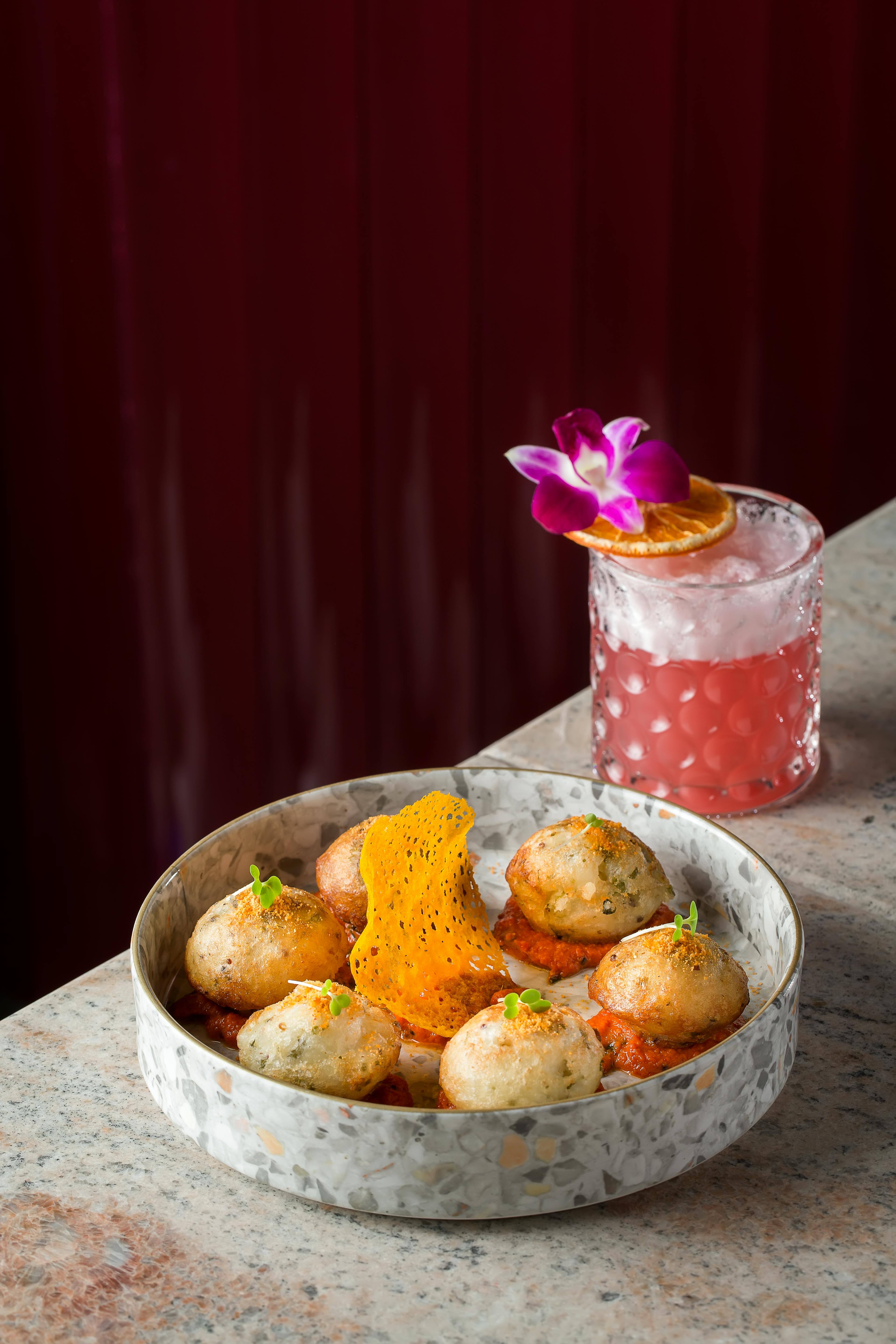 A stylish plate of Indian paddu with an elegant cocktail, perfect for culinary enthusiasts.