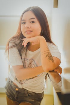 Chic young woman with long hair posing casually indoors, radiating confidence and style.